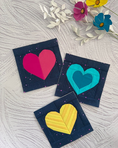 three foundation paper pieced heart blocks in vibrant colours on a dark background