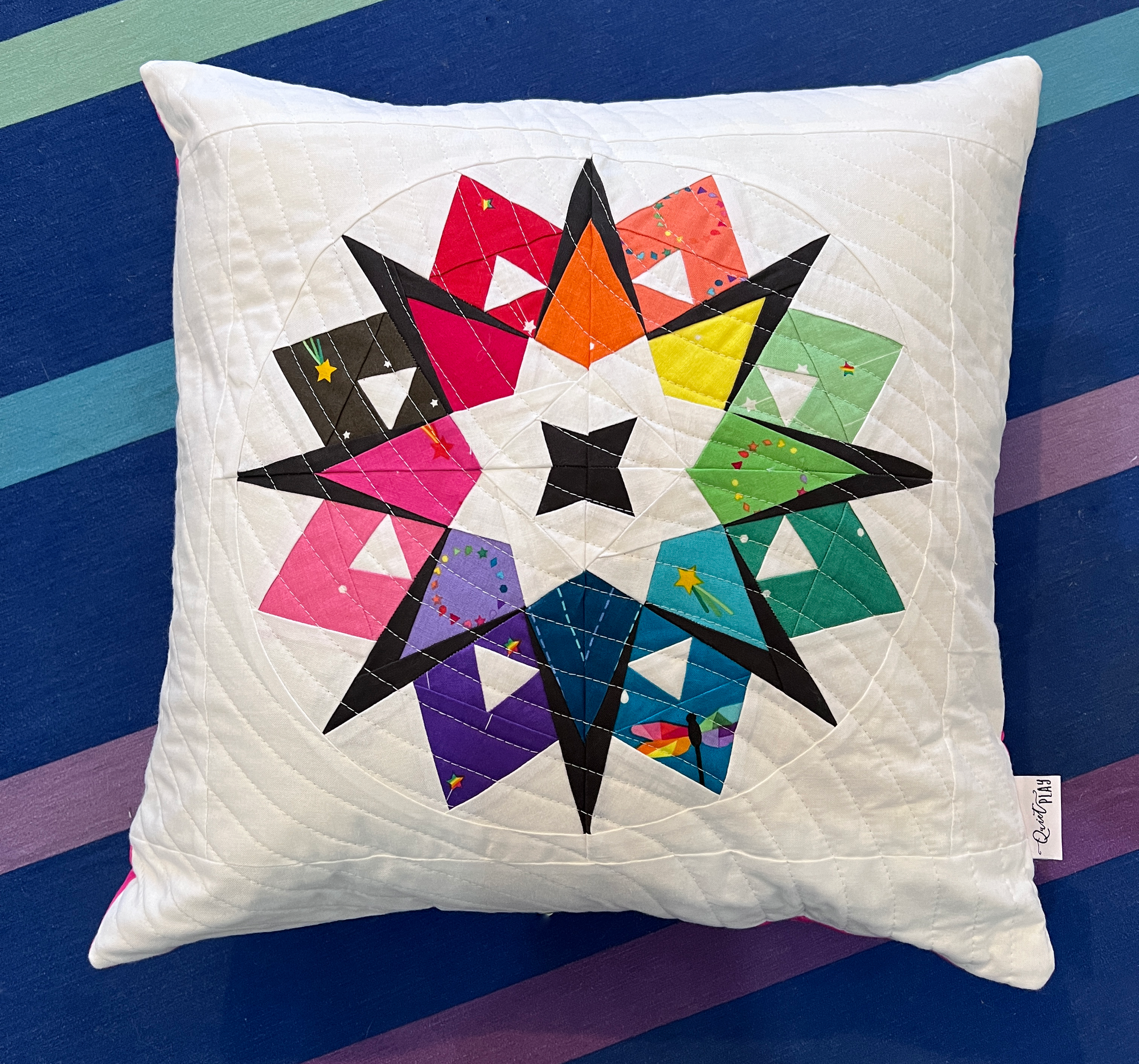 starburst paper pieced pattern made into a pillow wirh rainbow fabrics